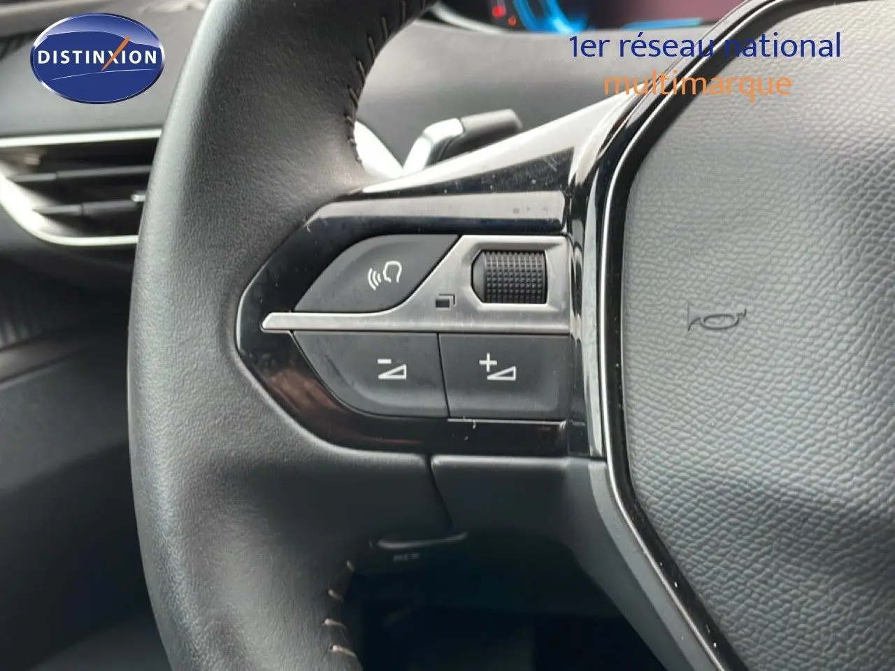 Gros plan sur les commandes gauche du volant noir du Peugeot 3008 hybride rechargeable 2024, avec boutons de réglage et molette.