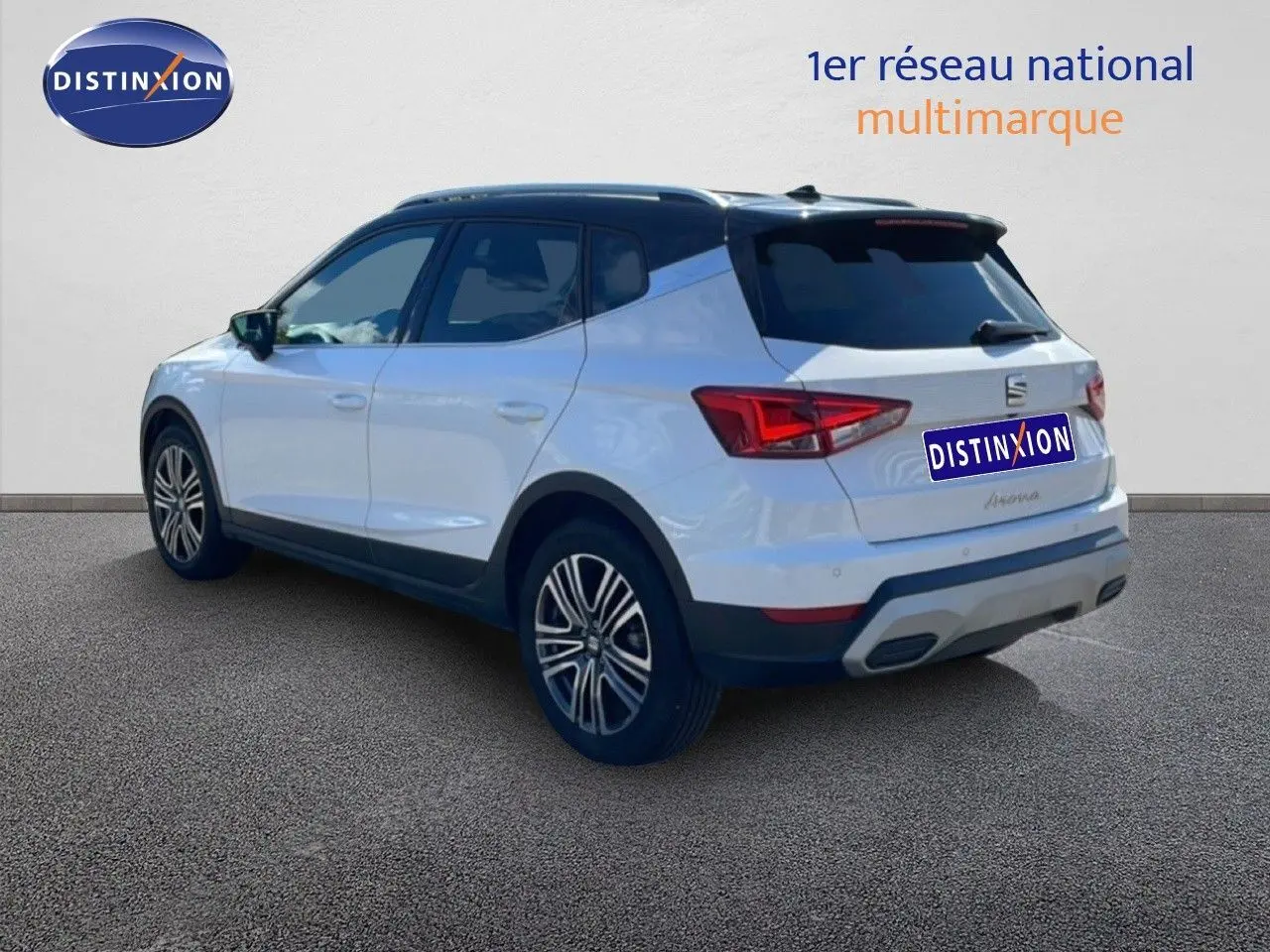 Vue 3/4 arrière droite d'un SEAT Arona blanc alpin avec toit noir et jantes alliage, sur fond neutre.
