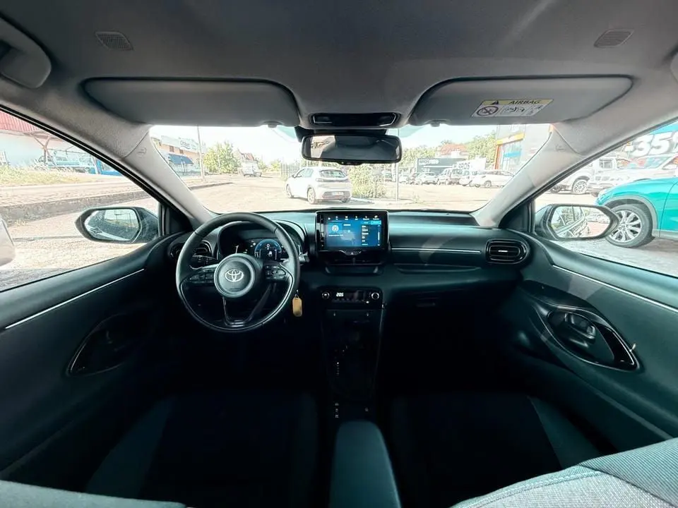Intérieur noir de la Toyota Yaris Hybrid 2025 vu de face, avec tableau de bord moderne et écran tactile central.