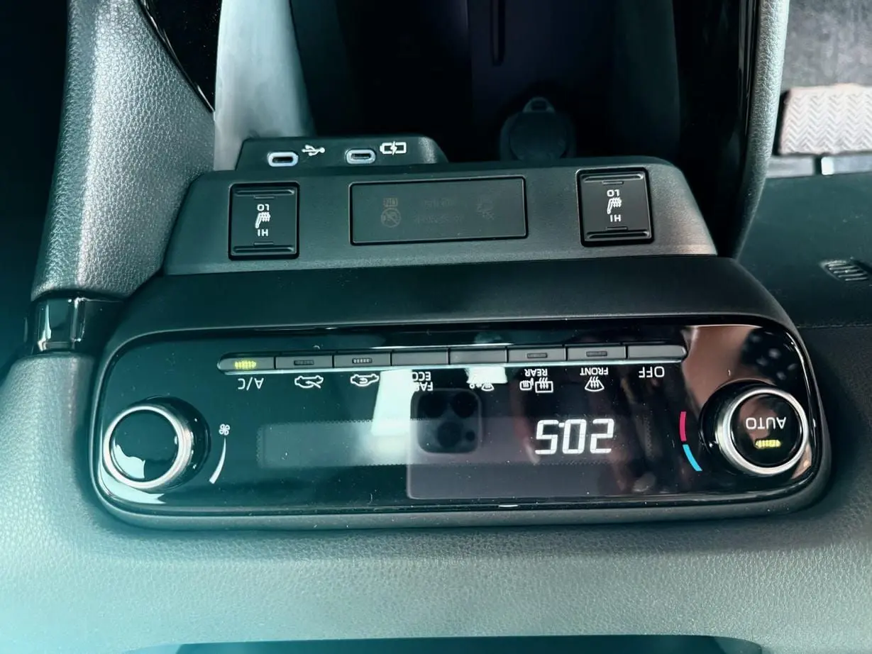 Vue rapprochée de la console centrale noire de la Toyota Yaris Hybrid 2025 avec commandes climatisation et ports USB.