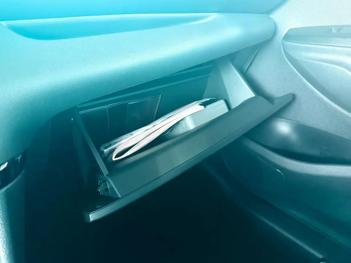 Gant de boîte à gants ouvert avec documents visibles dans l'habitacle d'une Toyota Yaris hybride 2025.