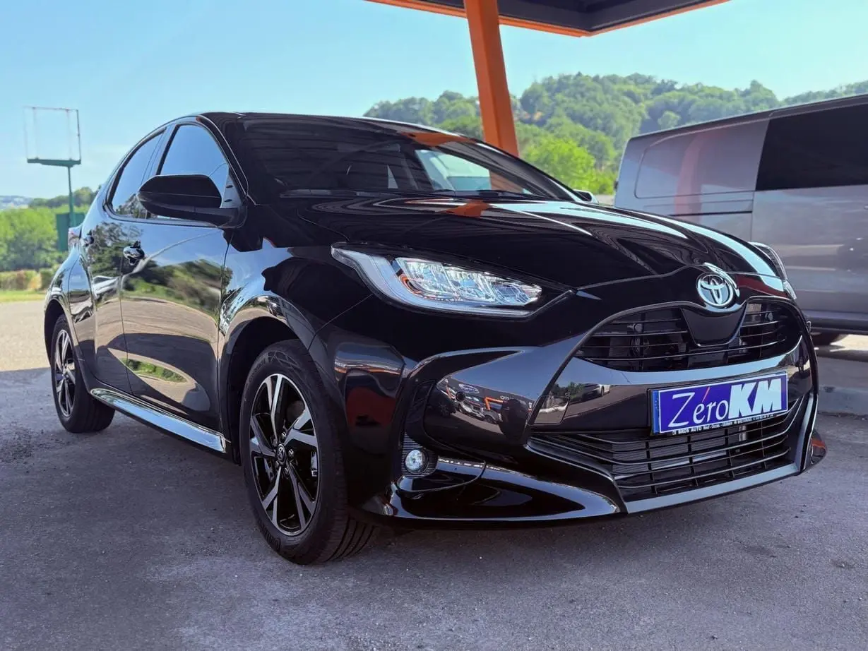 Toyota Yaris Hybrid noire vue en 3/4 avant gauche sous un abri avec jantes noires et phares LED.