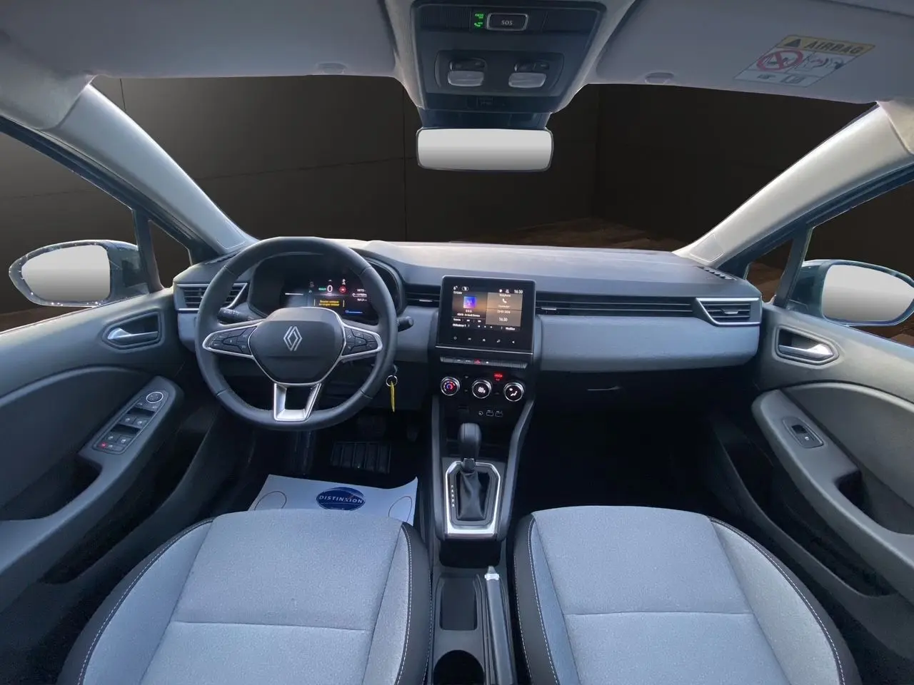 Vue intérieure avant de la Renault Clio V E-Tech gris schiste, avec tableau de bord moderne et écran tactile central.