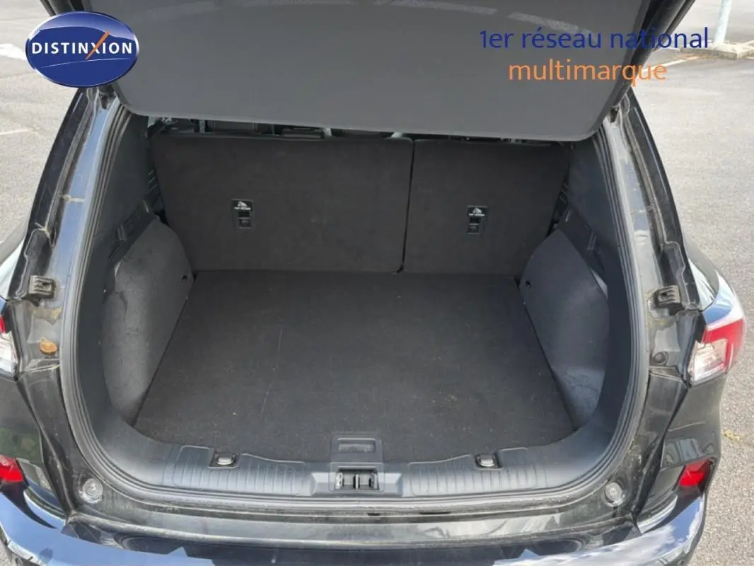 Coffre ouvert vu de l'arrière d'un Ford Kuga noir 2024, montrant un espace de chargement vide et propre.