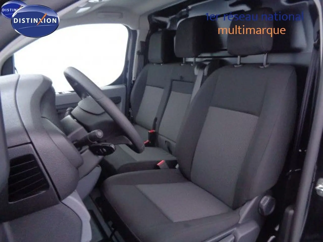 Intérieur du Peugeot Expert Fourgon 2022, vue côté conducteur sur les sièges tissu noir et gris, volant et tableau de bord visibles.