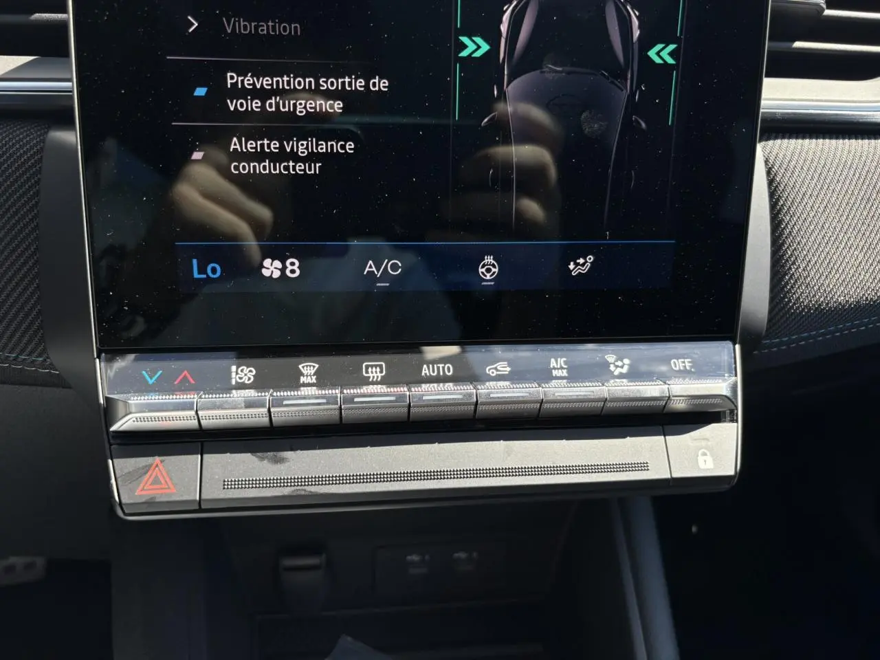 Gros plan sur la console centrale tactile du Renault Symbioz 2025 avec commandes climatisation et alertes sécurité affichées
