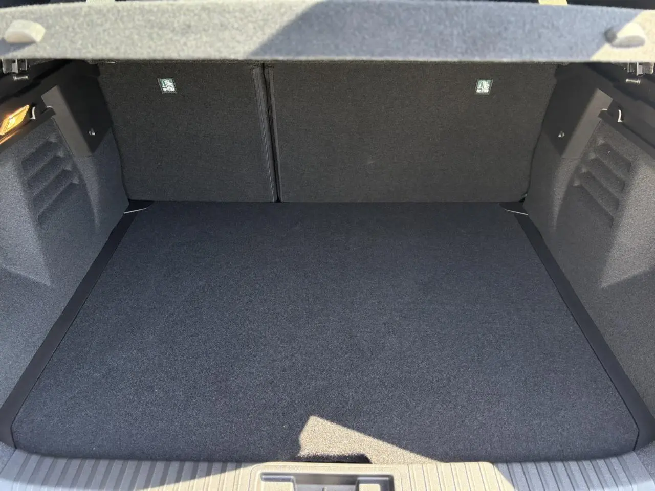 Coffre spacieux vu de face, intérieur gris foncé, sans chargement visible, Renault Symbioz 2025.