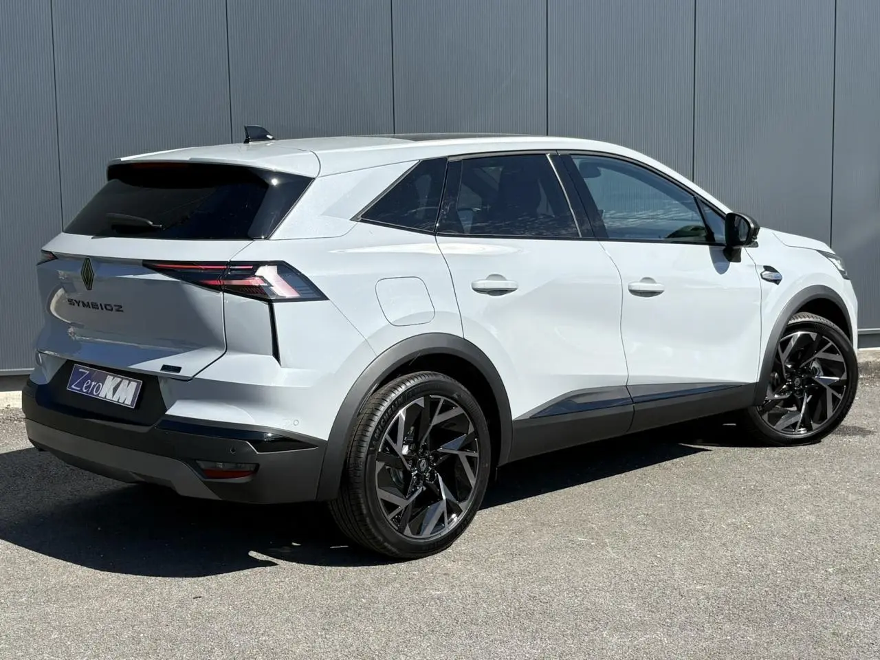 Vue 3/4 arrière droite d'un Renault SYMBIOZ gris clair avec jantes noires et vitres surteintées.