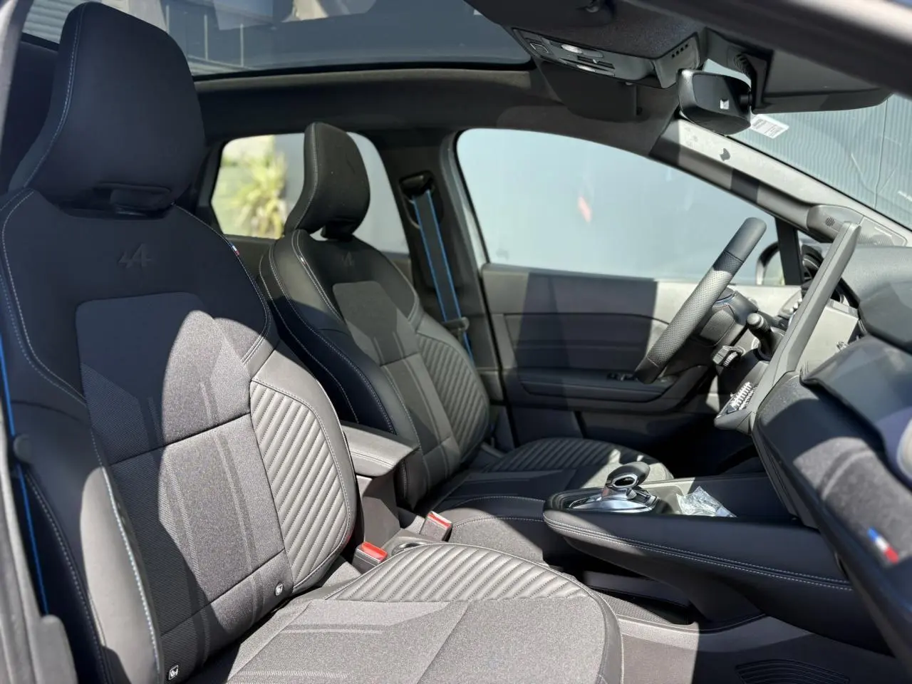 Vue intérieure côté conducteur du Renault SYMBIOZ 2025, sièges noirs avec surpiqûres bleues et toit panoramique Solarbay.