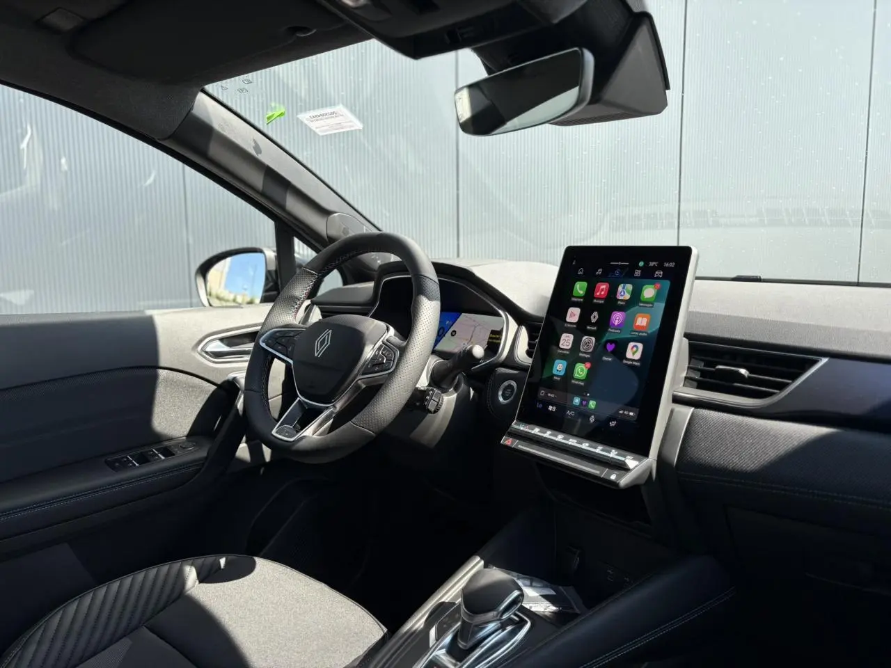 Intérieur Renault SYMBIOZ gris, vue côté conducteur sur volant, écran tactile vertical et tableau de bord moderne.