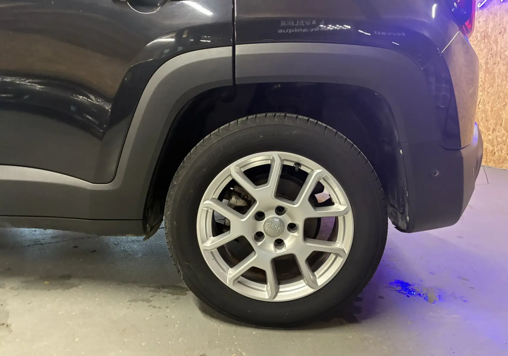 Gros plan sur la roue arrière droite d'un Jeep Renegade noir 2019, mettant en valeur la jante alu au design distinctif.