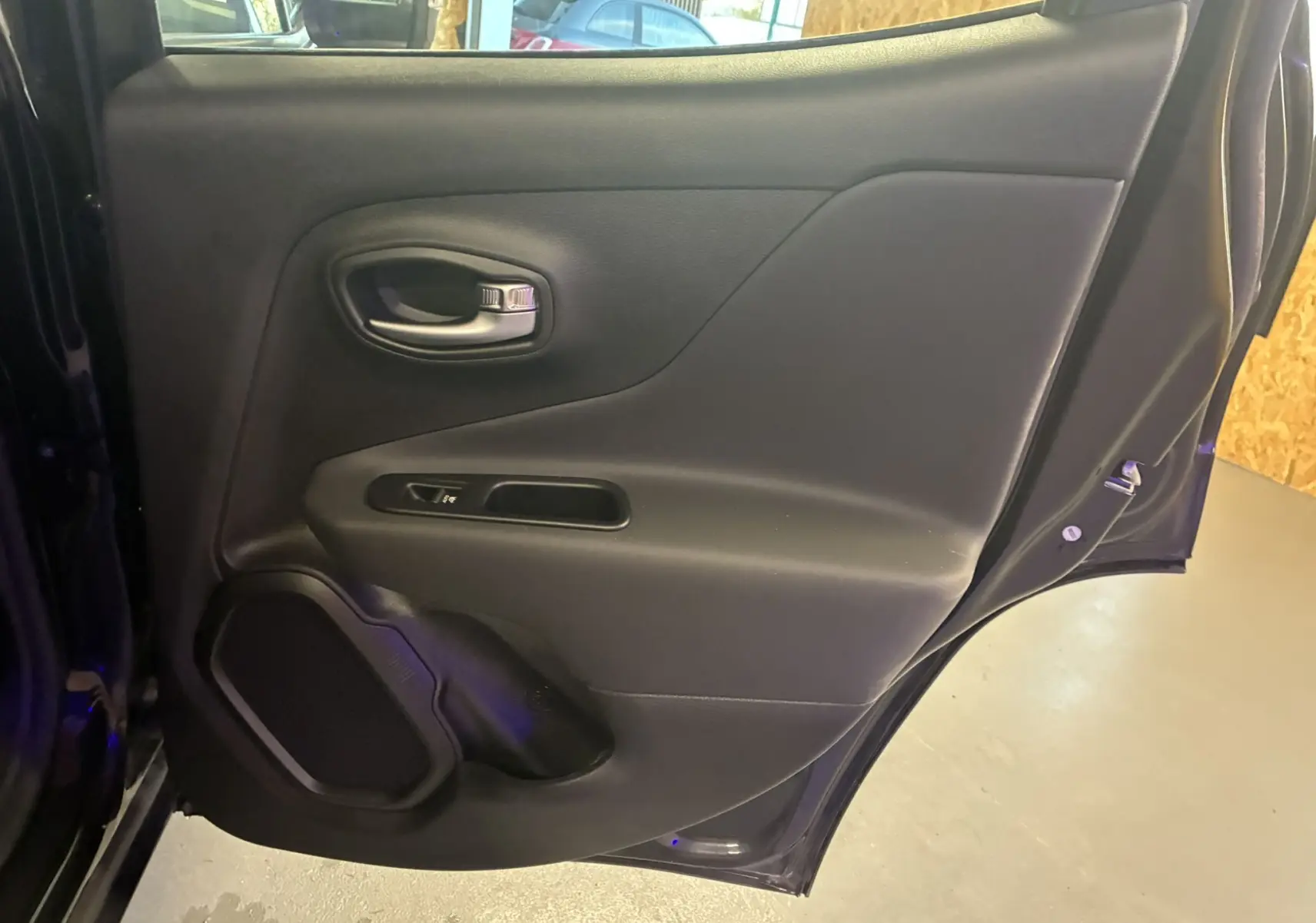 Porte arrière droite noire du Jeep Renegade 2019, montrant la poignée intérieure et le haut-parleur intégré.