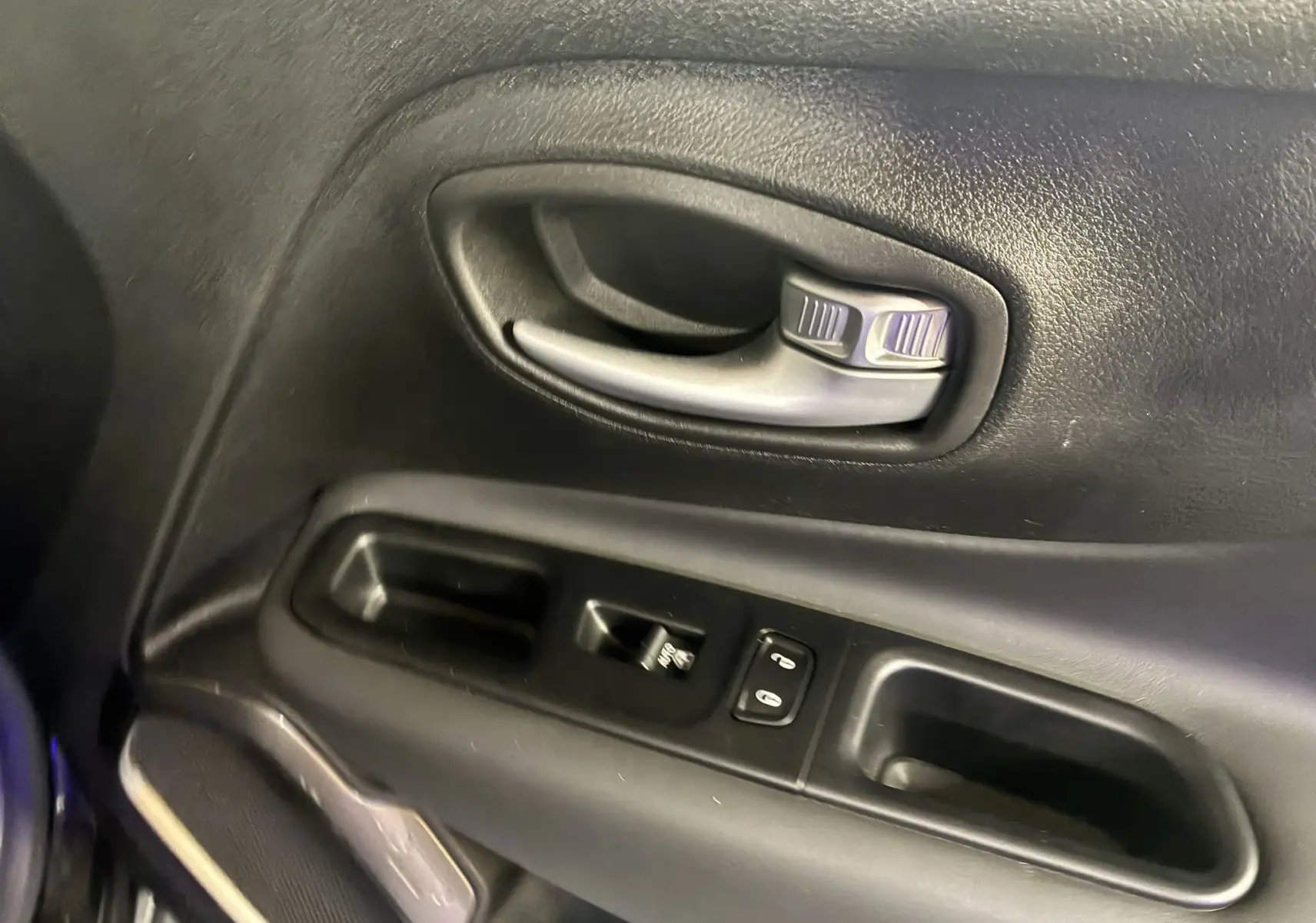 Poignée intérieure et commandes des vitres côté conducteur du Jeep Renegade noir, finition Limited 2019.