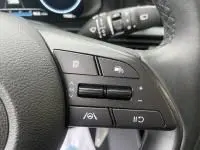 Gros plan sur les commandes au volant en cuir noir de la Hyundai i20 2025, avec boutons multifonctions et régulateur de vitesse.