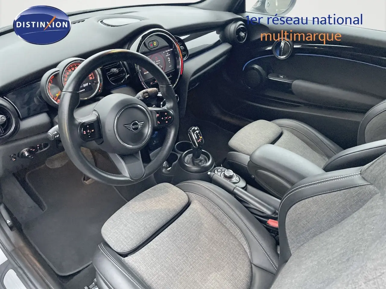 Intérieur de la MINI Cabriolet F57 2023, vue côté conducteur, sièges tissu gris et cuir noir, tableau de bord moderne.