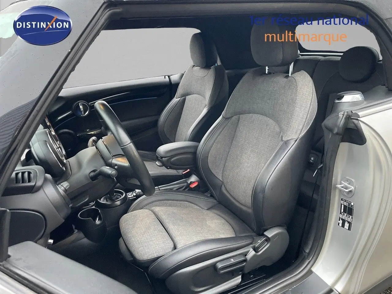 Intérieur de MINI Cabriolet Melting Silver, vue côté gauche sur sièges tissu gris et cuir noir, volant et tableau de bord visibles.