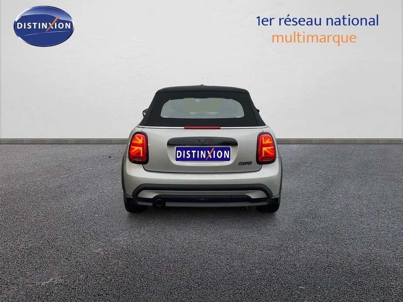 Vue arrière d'une MINI Cabriolet Melting Silver 2023 avec toit noir et feux arrière LED allumés.