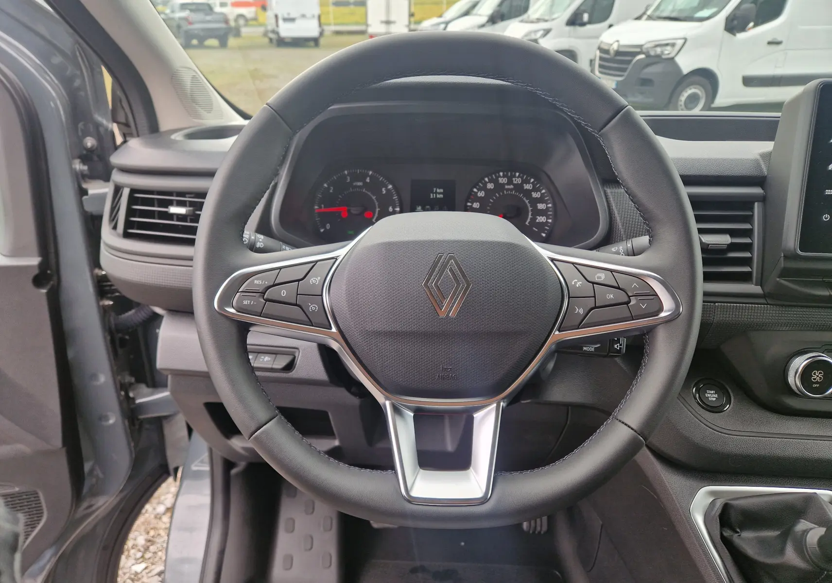 Vue centrée sur le volant noir du Renault Trafic Fourgon gris urbain 2025 avec commandes intégrées et tableau de bord visible.