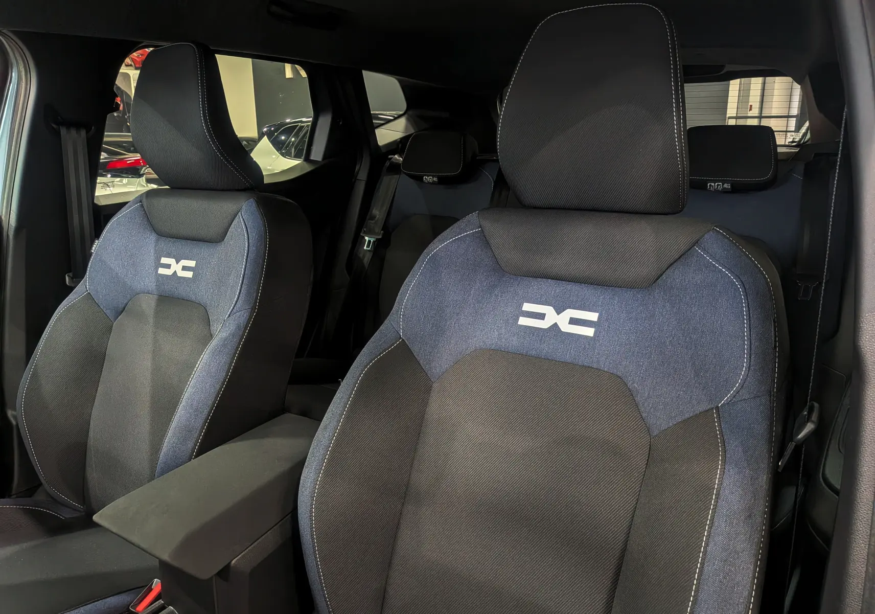 Gros plan sur les sièges avant en tissu bleu et noir du Dacia Duster 2025, avec logo distinctif brodé.