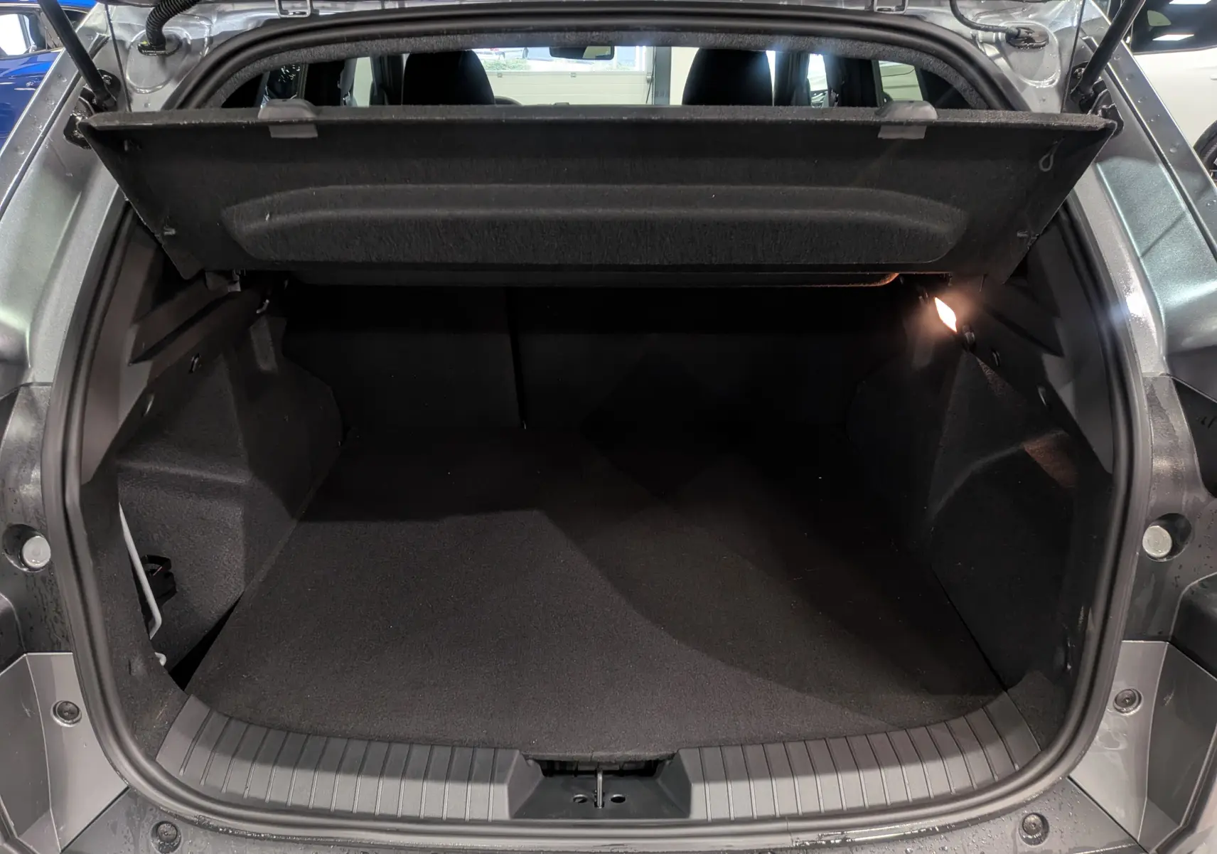 Coffre ouvert vu de l'arrière d'un Dacia Duster gris schiste 2025, montrant un espace de chargement propre et spacieux.