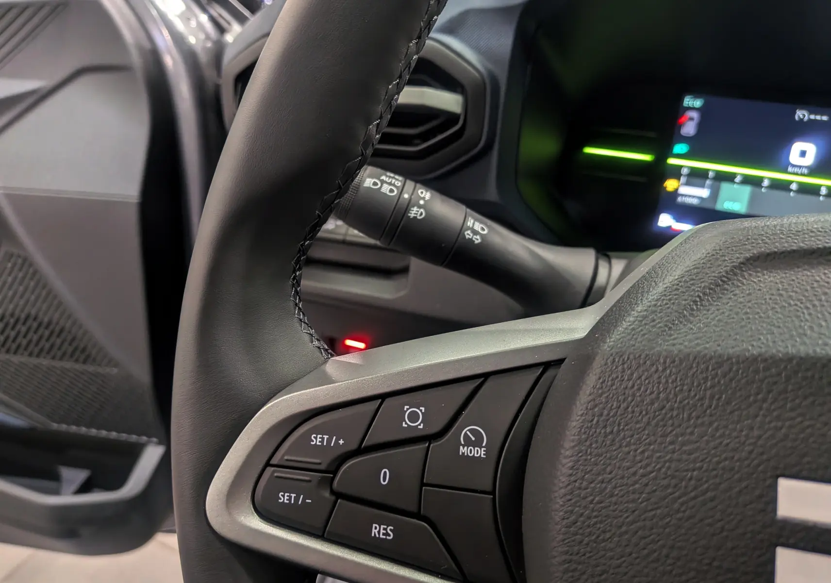 Gros plan sur le volant du Dacia Duster 2025, montrant les commandes de régulateur de vitesse et le tableau de bord numérique.