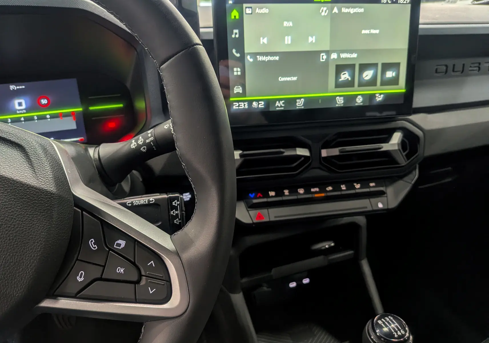 Vue rapprochée de l'intérieur du Dacia Duster gris Schiste 2025, montrant le volant, la boîte manuelle et l'écran tactile central.