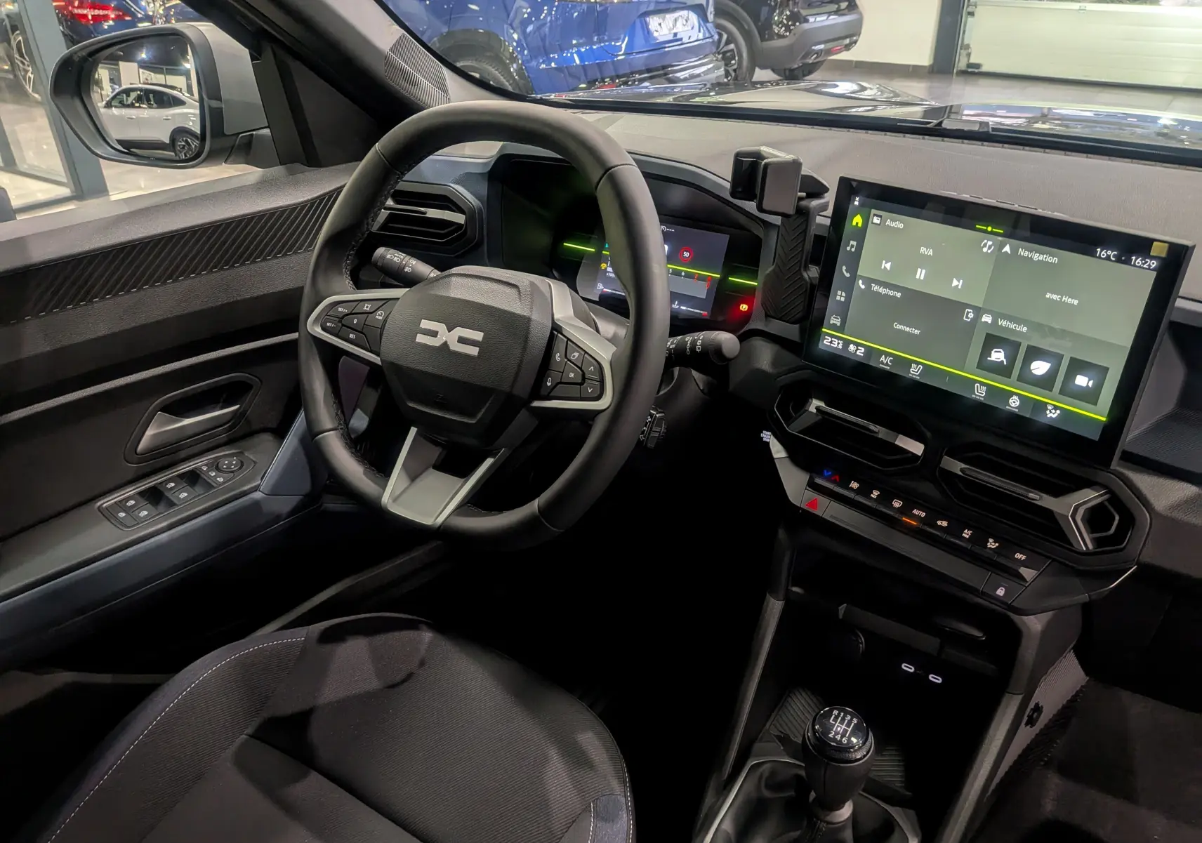Intérieur du Dacia Duster 2025 avec vue sur le volant multifonction, écran tactile et levier de vitesse manuel.