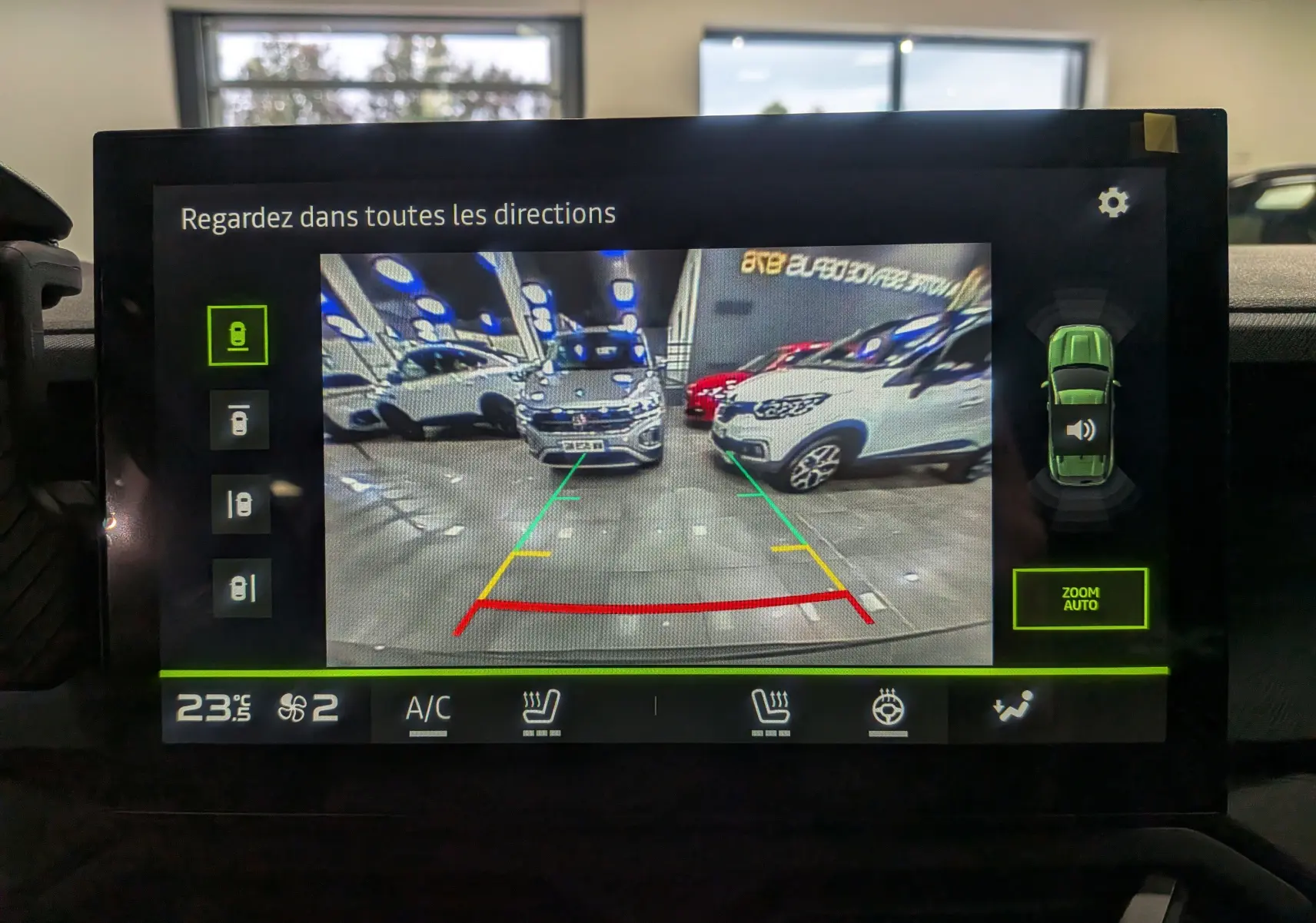 Écran de caméra de recul montrant un Dacia Duster gris schiste en vue arrière dans un garage lumineux.