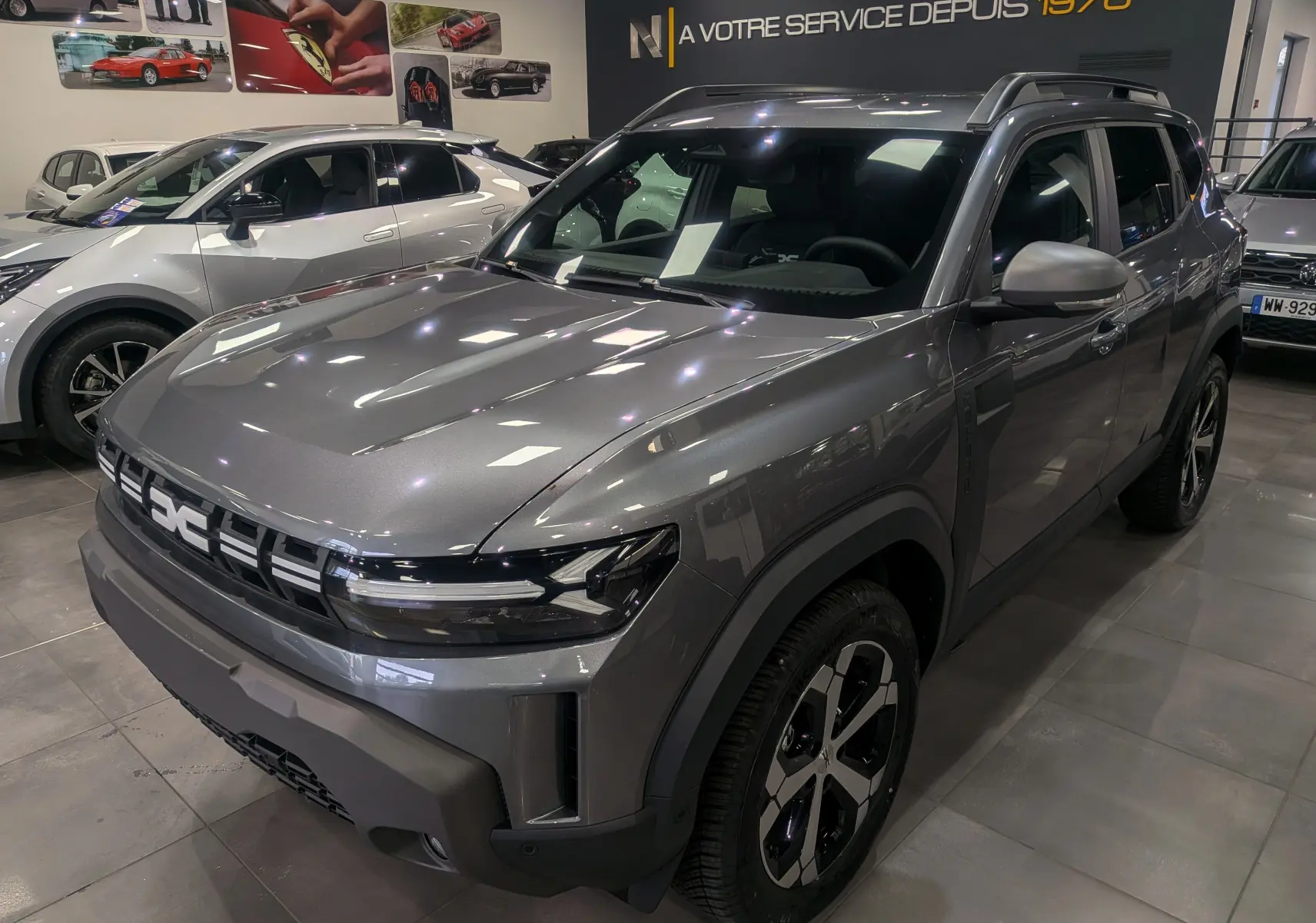 SUV Dacia Duster gris schiste vu en 3/4 avant droit, avec calandre moderne et jantes bi-ton noires.