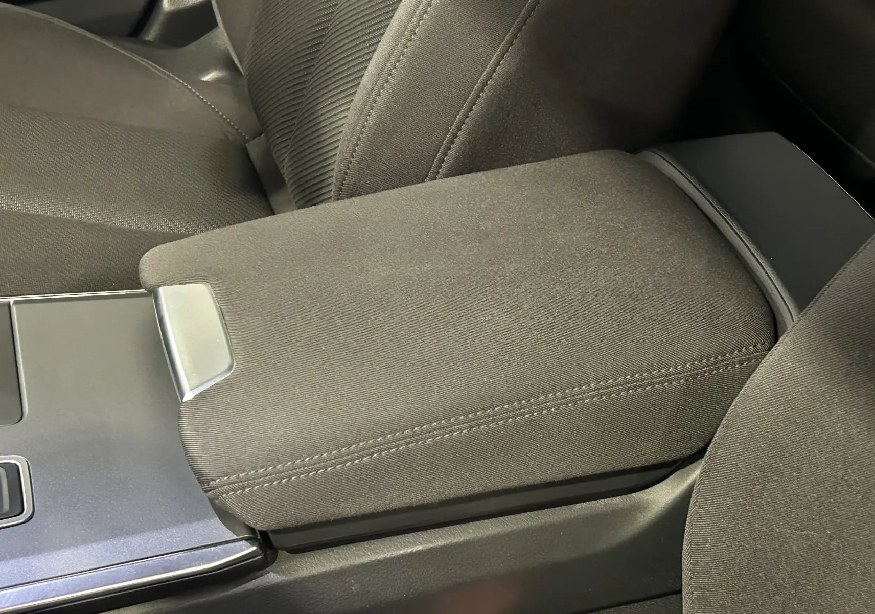 Gros plan sur l'accoudoir central en tissu noir et la console centrale d'une Audi A6 Avant 40 TDI 2019.