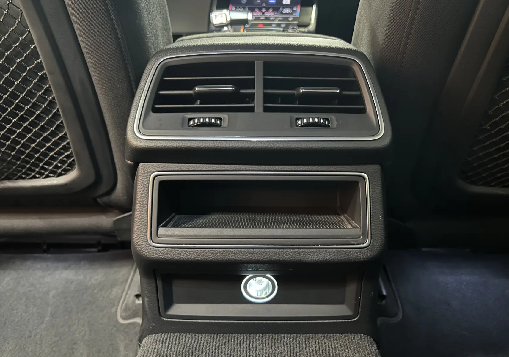 Détail de la console arrière noire avec bouches d'aération et prise allume-cigare dans une Audi A6 Avant 2019.