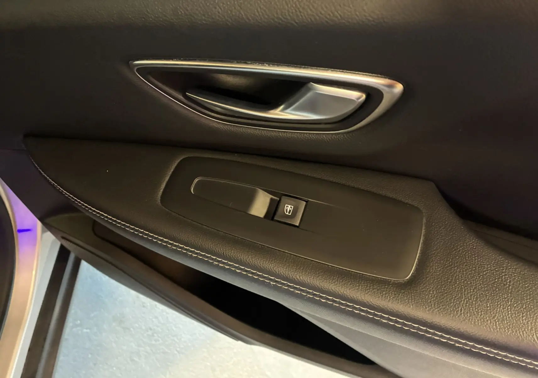 Poignée de porte intérieure côté gauche en cuir noir avec bouton de commande de vitre du Renault Grand Scenic gris 2017.