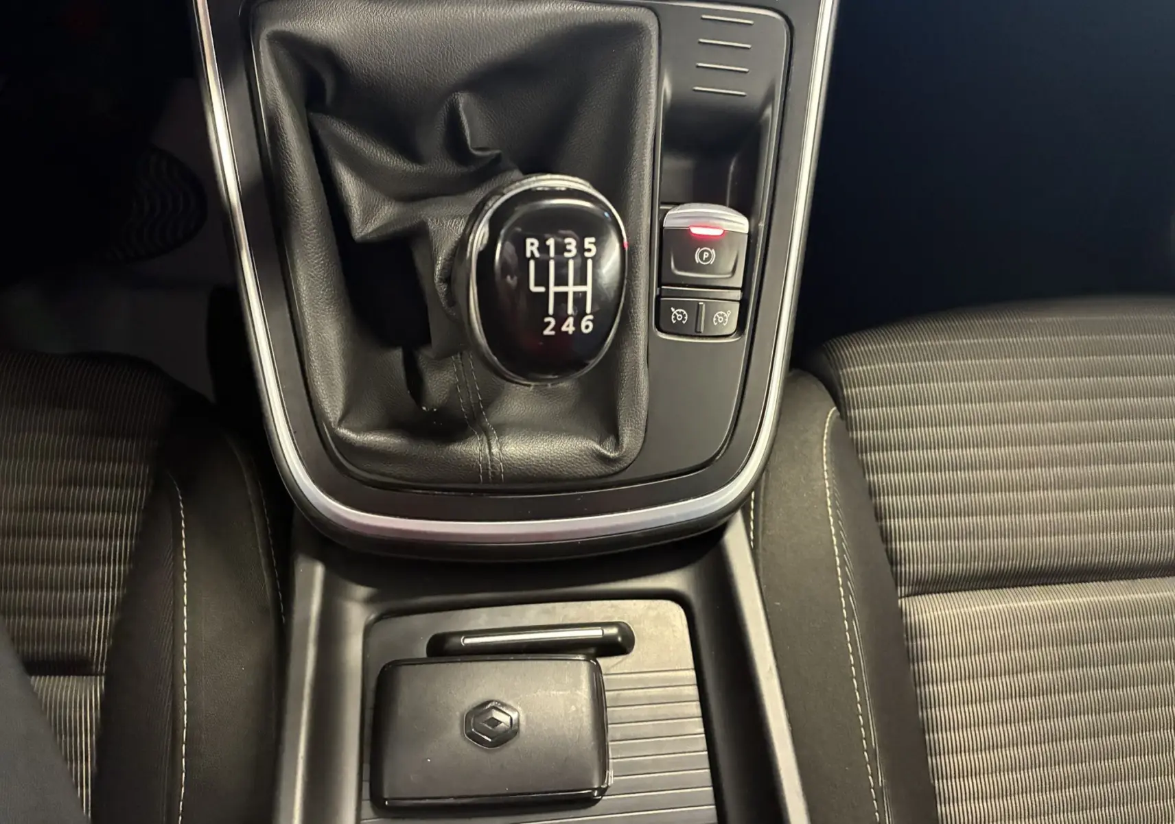 Vue rapprochée de la boîte manuelle et du levier de vitesses noir du Renault Grand Scenic gris, avec clé Renault posée.