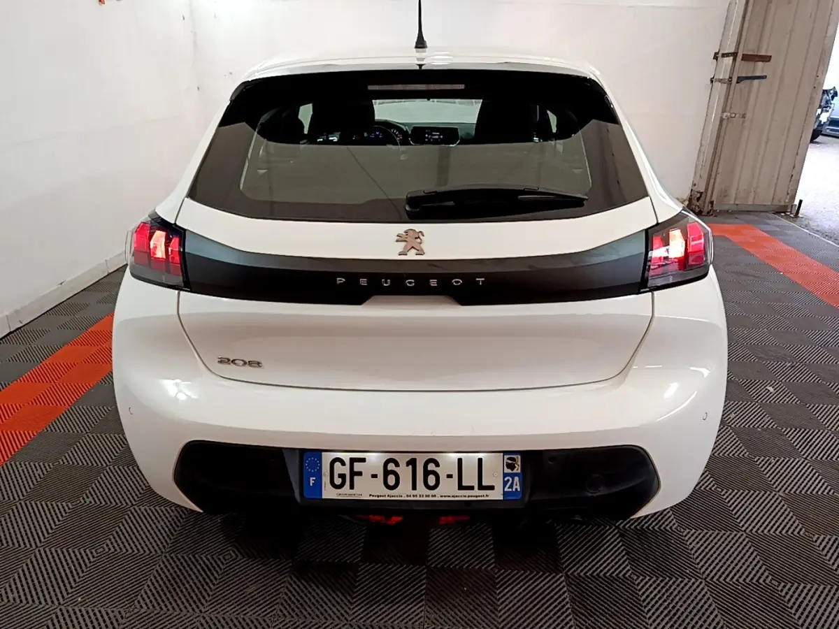 Vue arrière d'une Peugeot 208 blanche de 2022 avec feux arrière allumés dans un garage.