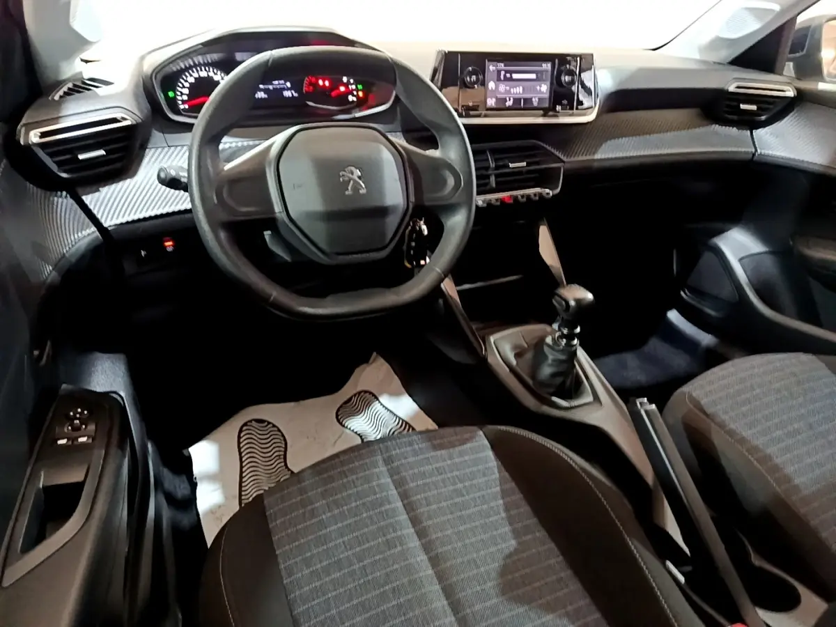Vue intérieure avant de la Peugeot 208 1.5 BlueHDi 2022, volant compact, tableau de bord numérique et boîte manuelle.
