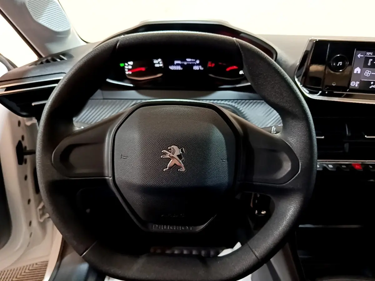 Vue rapprochée du volant noir de la Peugeot 208 1.5 BlueHDi 2022 avec tableau de bord et écran tactile visibles.