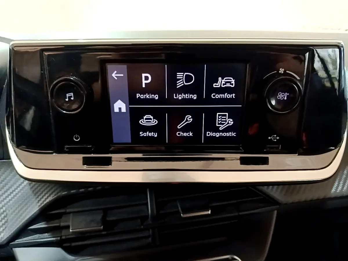 Écran tactile central noir affichant les options de conduite dans l'habitacle d'une Peugeot 208 blanche.