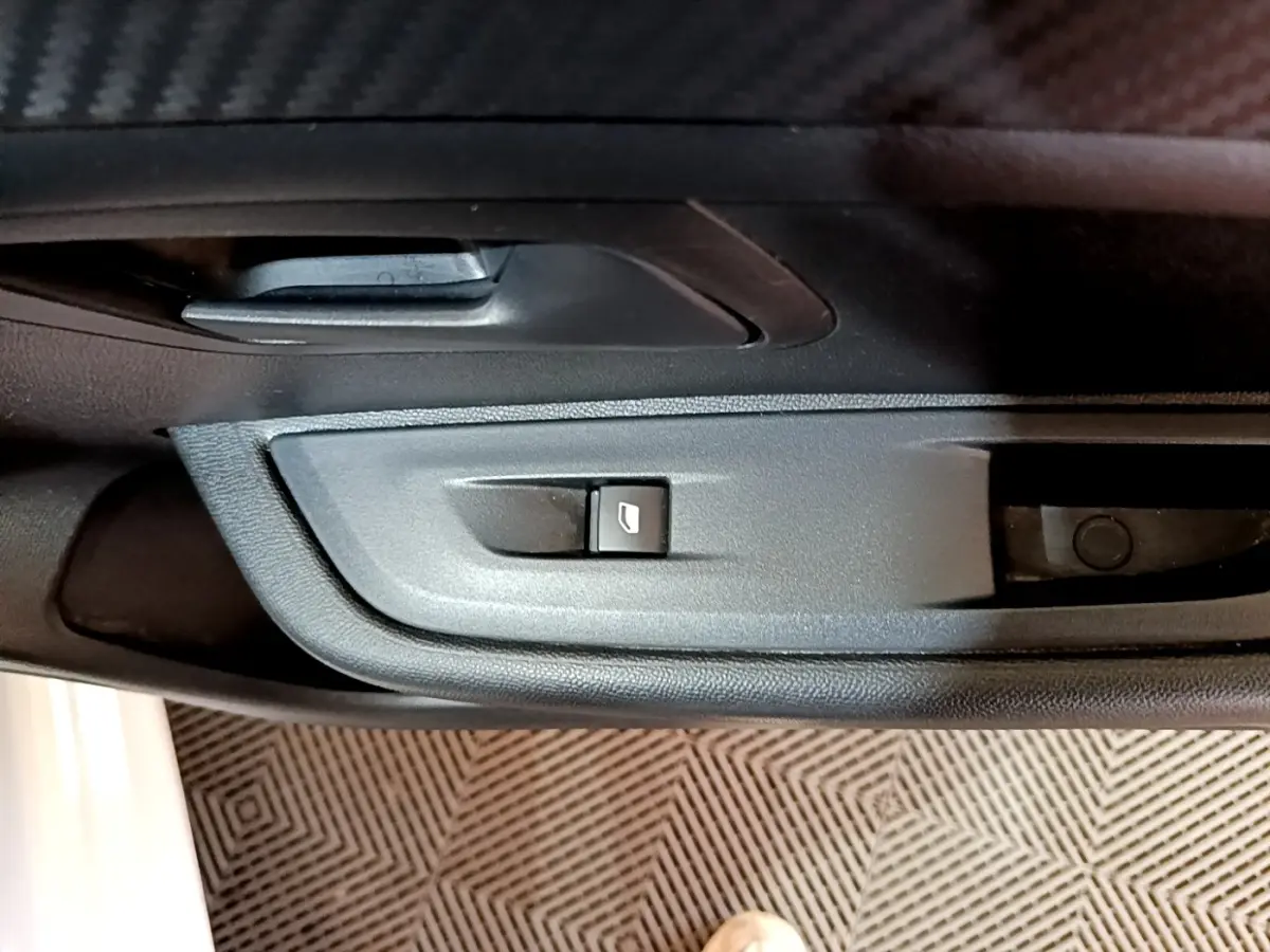 Détail de la commande de lève-vitre côté conducteur dans l'intérieur noir d'une Peugeot 208 blanche 2022.
