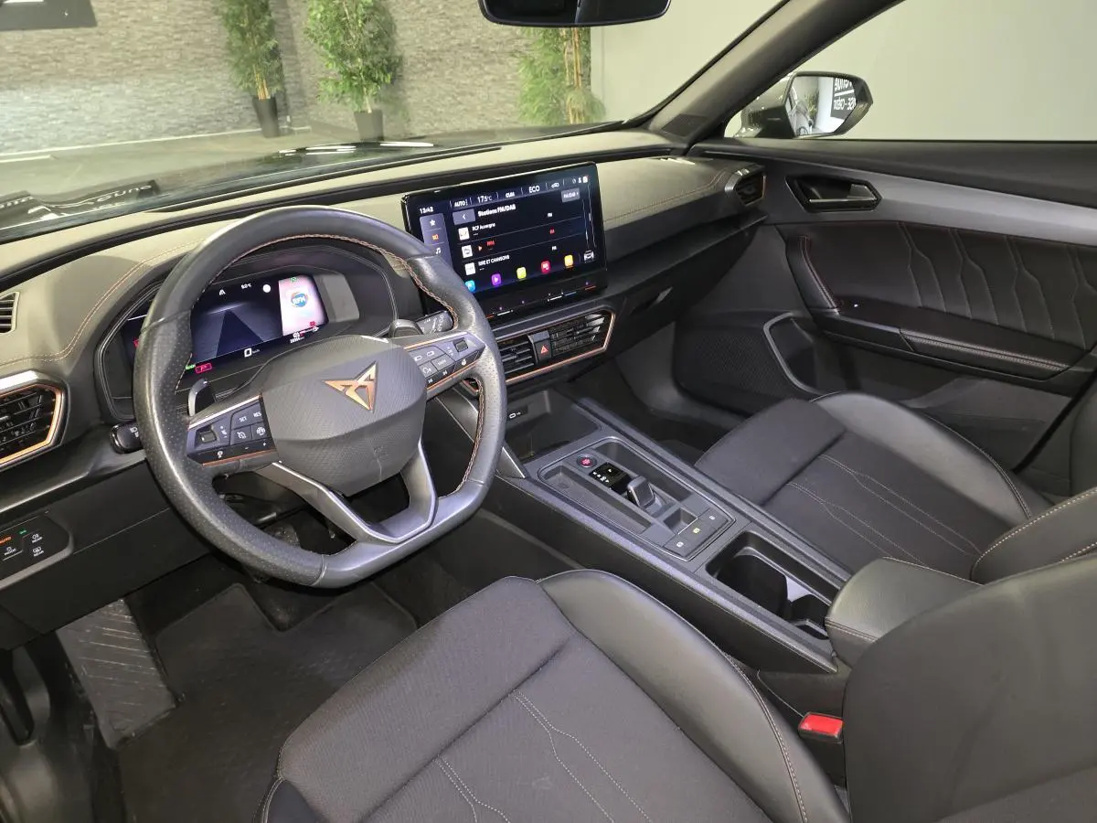 Intérieur de la CUPRA Formentor 1.4 e-Hybrid 2023 vu côté conducteur, tableau de bord noir avec écran tactile et volant sport cuir.