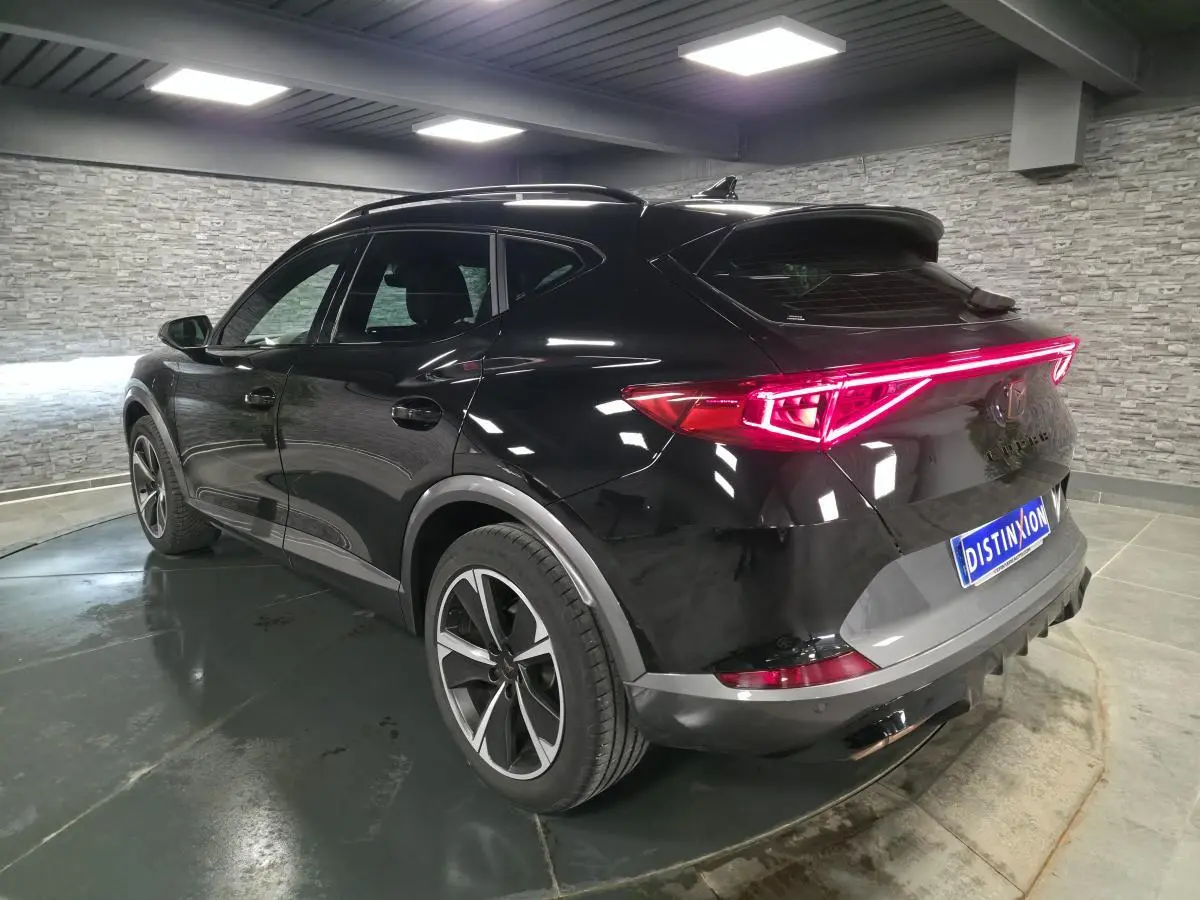 Vue 3/4 arrière droite du CUPRA Formentor noir Minuit avec bandeau LED arrière Infinite Light allumé.