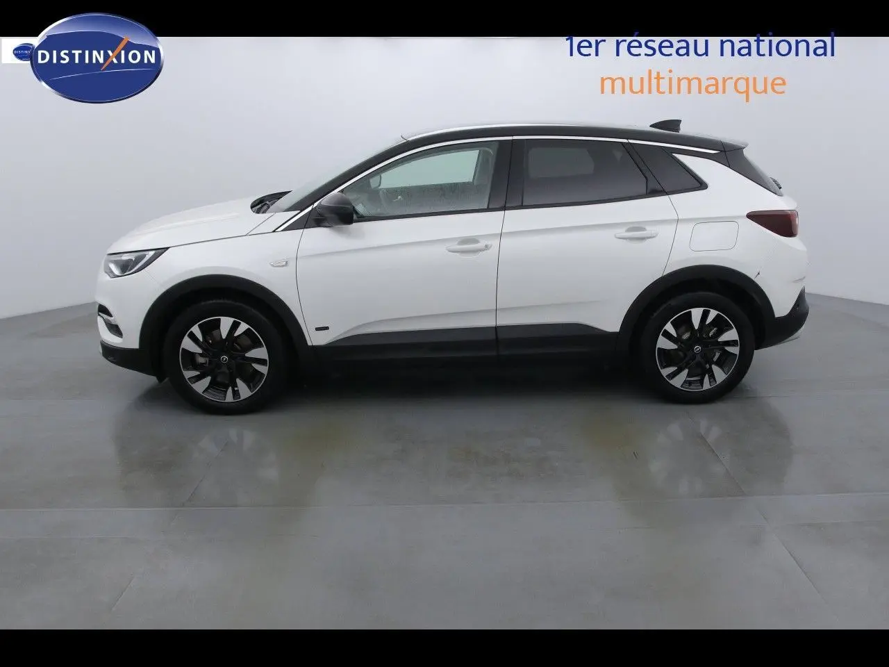 Profil côté gauche d'un Opel Grandland X blanc nacré hybride rechargeable de 2021 avec jantes noires et toit noir contrasté.