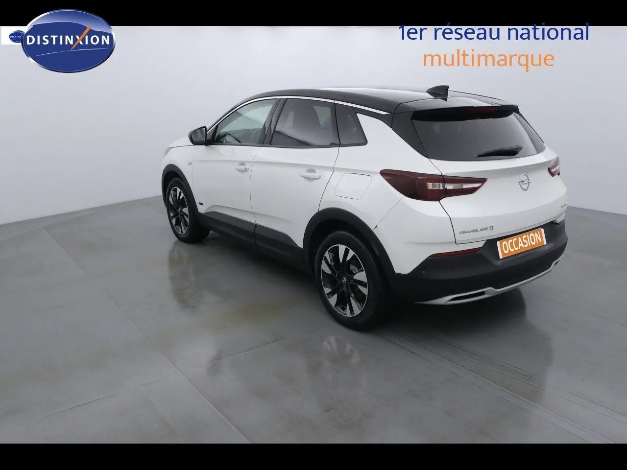 Opel Grandland X blanc nacré métal vu en 3/4 arrière droit, toit noir contrasté et jantes noires distinctives.