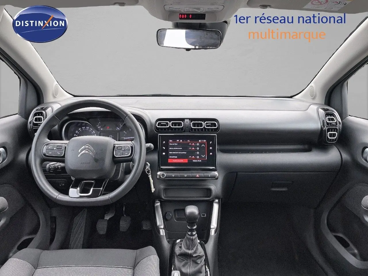 Tableau de bord et volant noir de la Citroën C3 Aircross 2023 vus de face, avec écran tactile central allumé.