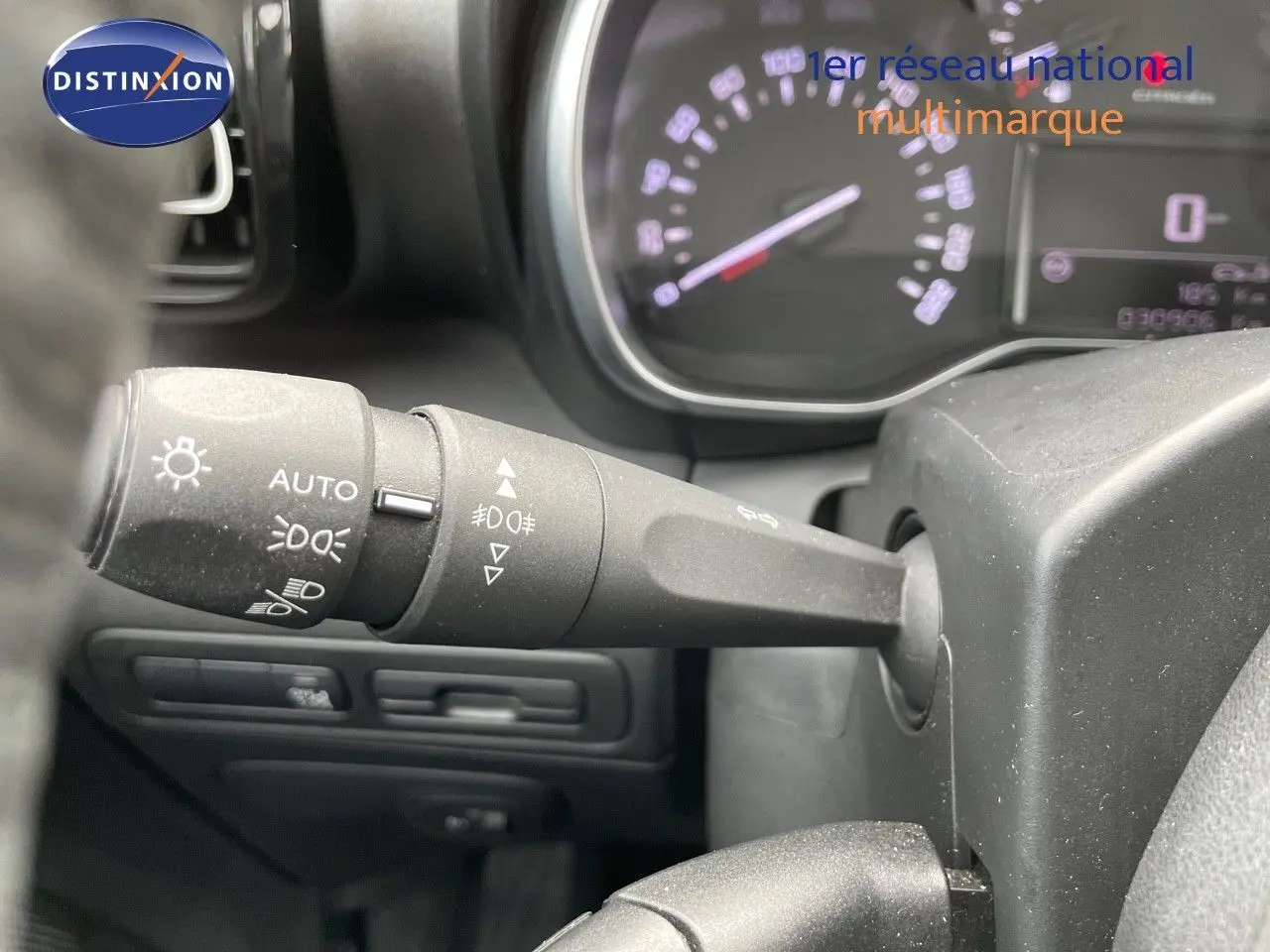 Gros plan sur la manette des feux d’un Citroën C3 Aircross blanc polaire, tableau de bord en arrière-plan flou.