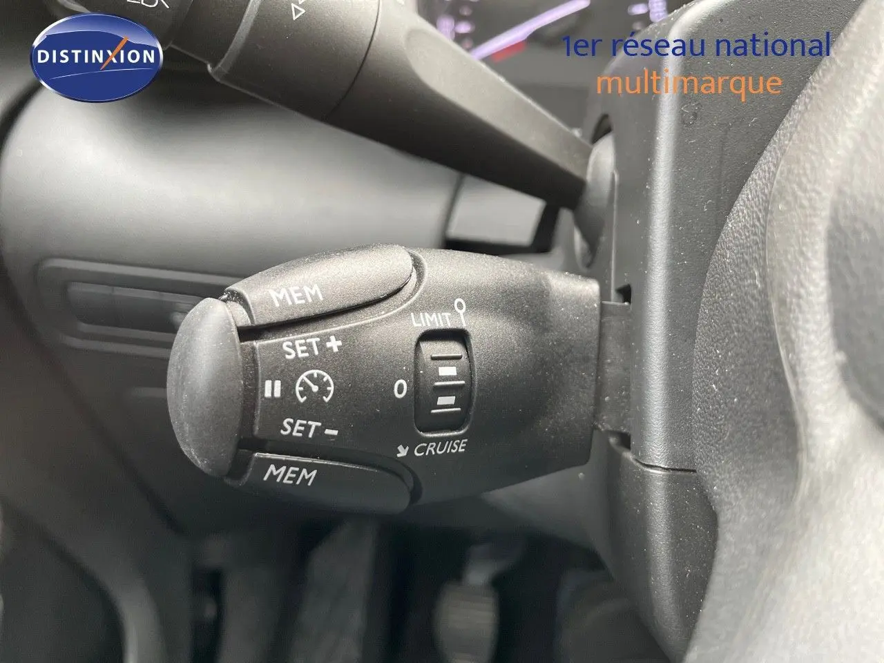 Gros plan sur la commande de régulateur de vitesse du Citroën C3 Aircross blanc polaire, version 2023, intérieur conducteur.