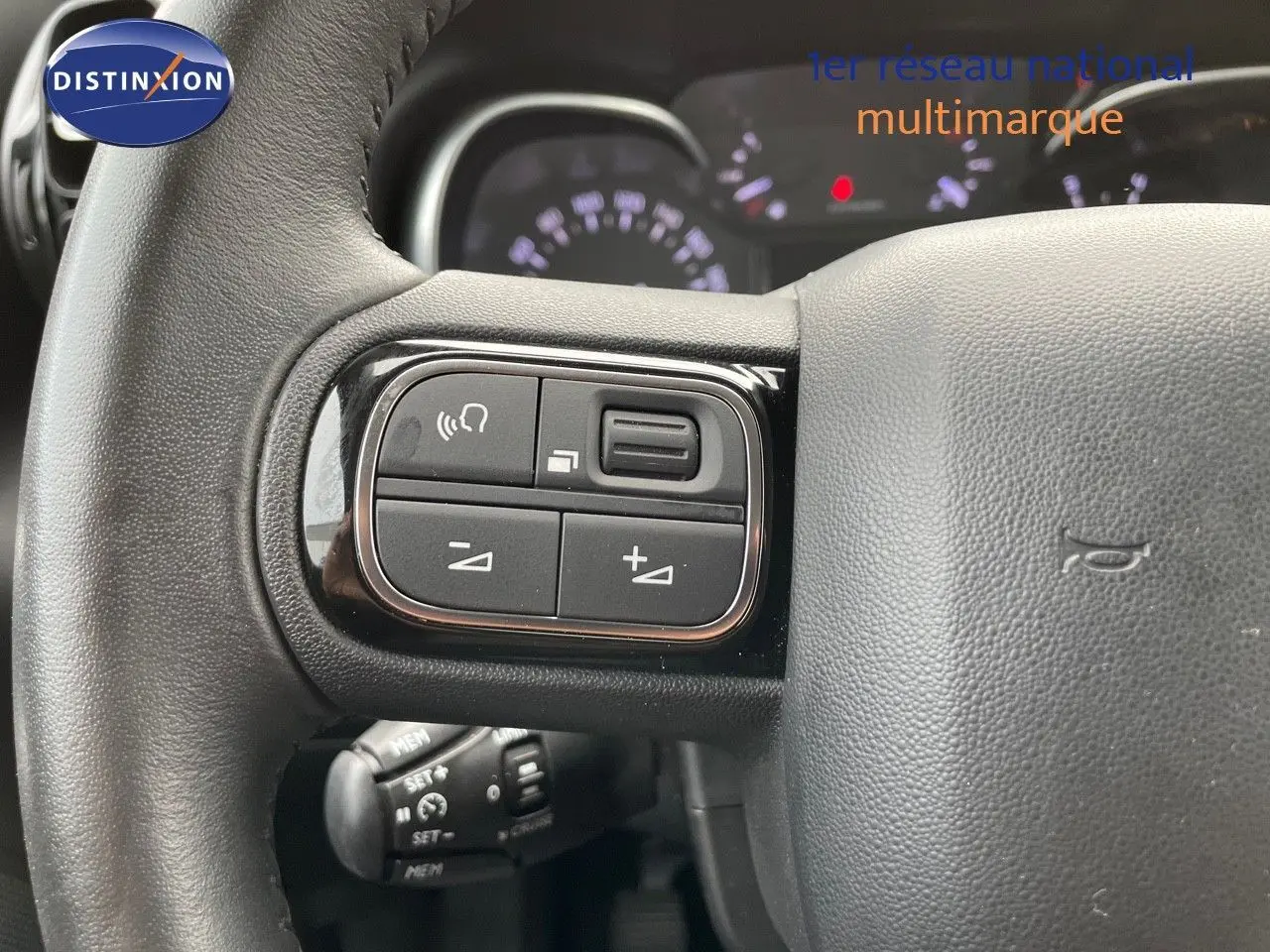 Gros plan sur les commandes du volant du Citroën C3 Aircross 2023 en blanc polaire, mettant en valeur les boutons multifonctions.