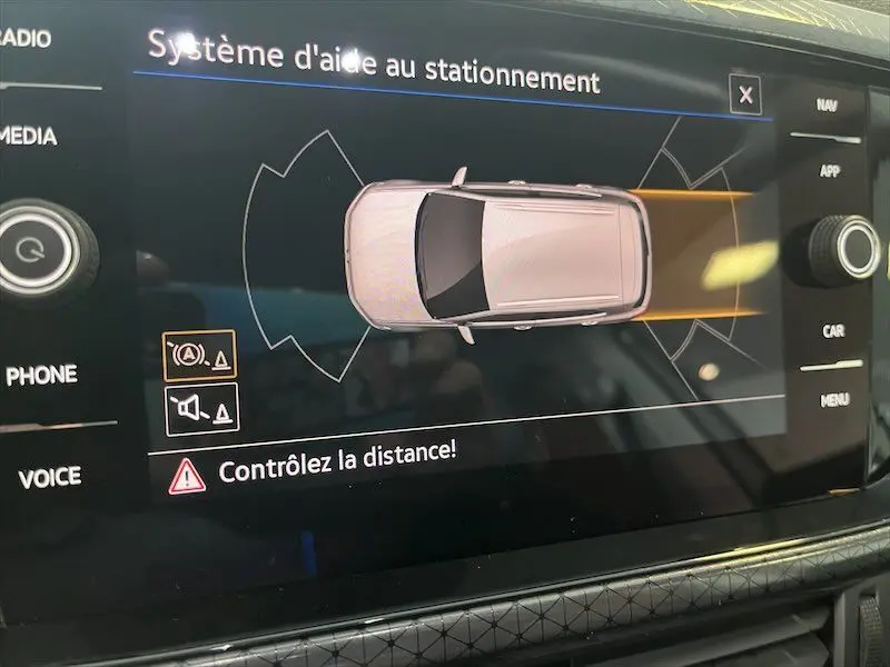 Affichage du système d'aide au stationnement sur l'écran intérieur du Volkswagen T-Cross gris Limestone, vue en plan du véhicule.