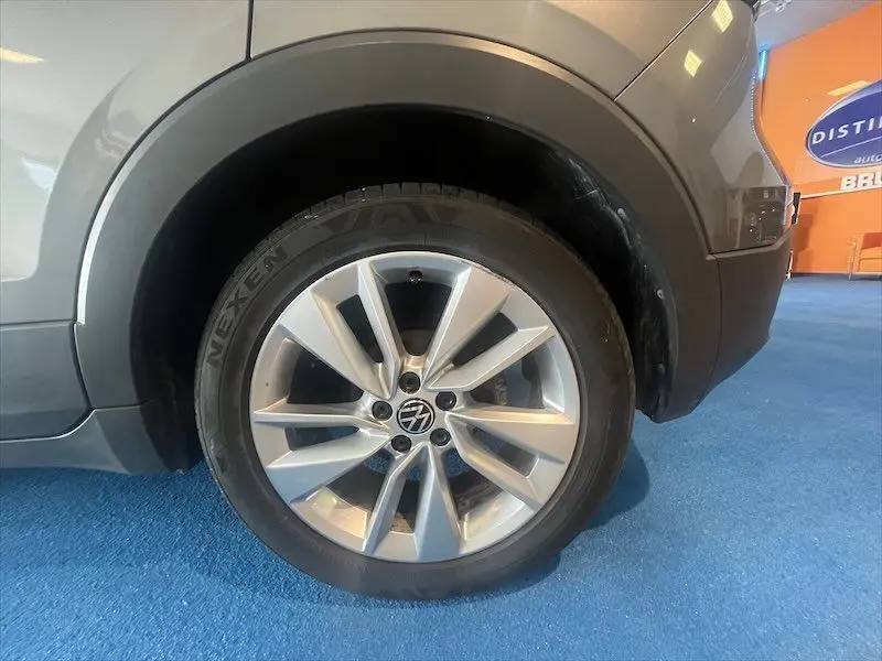 Gros plan sur la roue avant droite d'un Volkswagen T-Cross gris Limestone métallisé, avec jante en alliage et pneu Nexen.