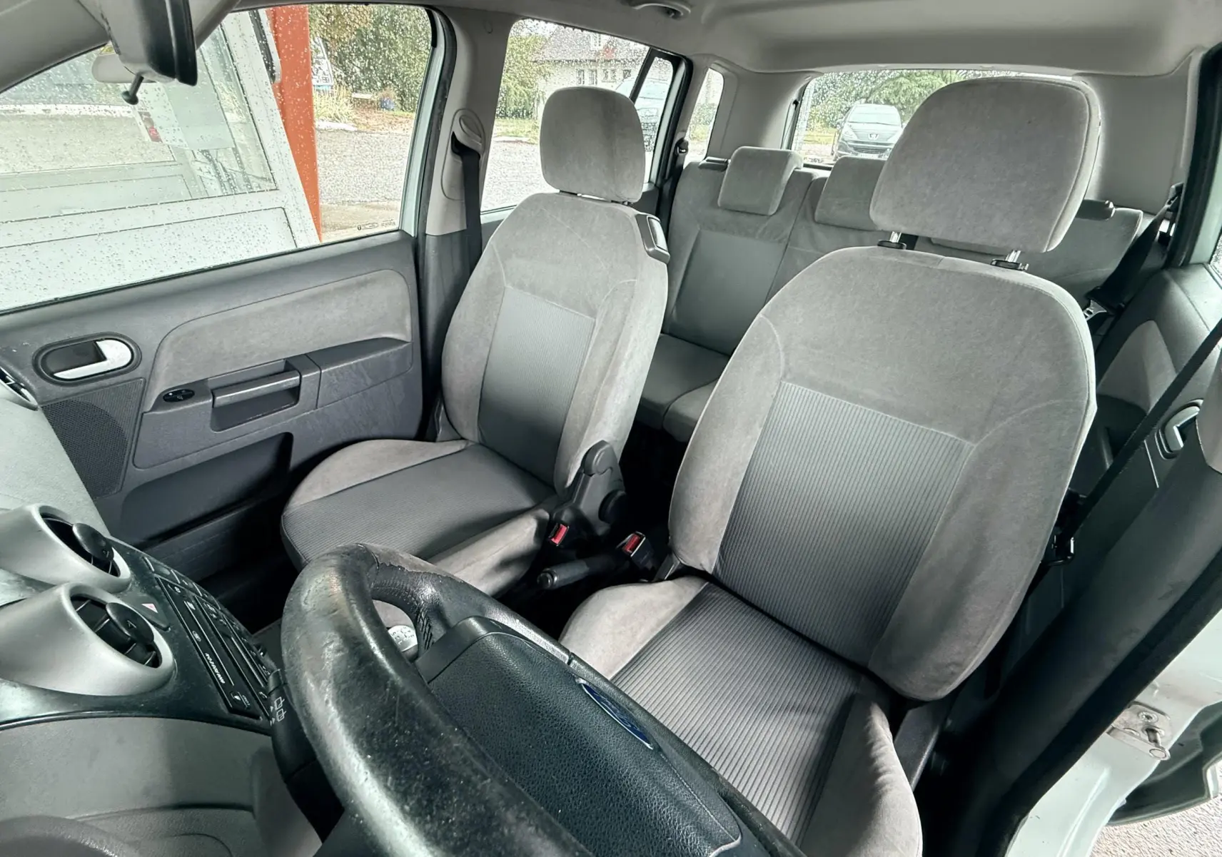 Vue intérieure de la Ford Fusion 2002 montrant les sièges avant gris et le volant côté gauche.