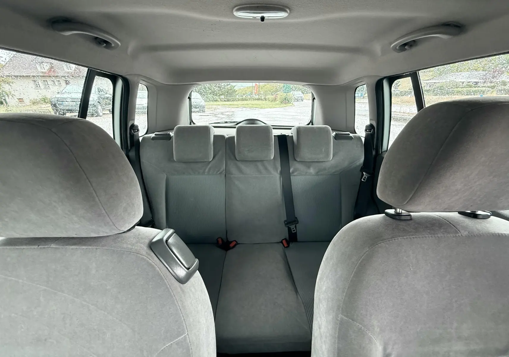 Vue intérieure arrière montrant les sièges gris clair d'une Ford Fusion 2002, avec trois appuie-têtes et ceinture centrale.